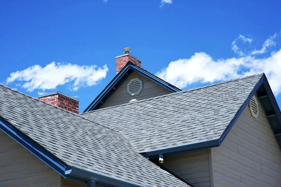Completed architectural shingle roof with two brick chimneys